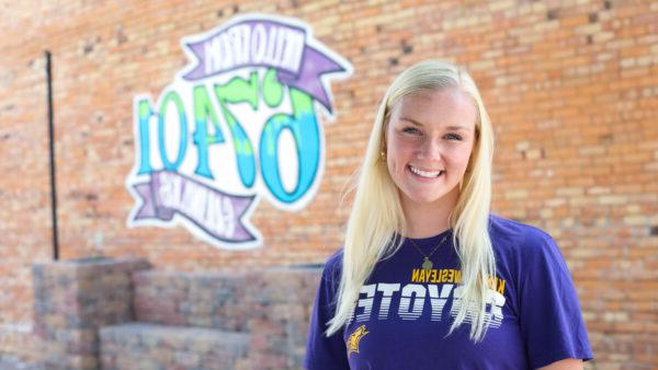 KWU student in front of downtown mural